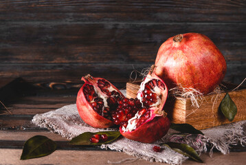 Wall Mural - red open pomegranate, a whole pomegranate in a box on a dark wooden background