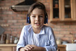 © fizkes - Portrait of cute gen Z school boy in headphones speaking at webcam during video call. Kid learning online, studying from home, using gadget for virtual talk to teacher. Screen view head shot