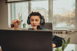 © Minet - little boy using laptop and headphones studying math during his online lesson at home, social distance during quarantine, self-isolation. takes notes. E-Education Distance Home Education.