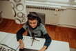 © Minet - Top view, the little boy using laptop and headphones studying math during his online lesson at home, social distance during quarantine, self-isolation. takes notes.