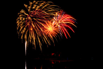 Wall Mural - Holiday fireworks above water with reflection in the water