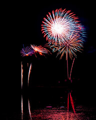 Wall Mural - Holiday fireworks above water with reflection in the water