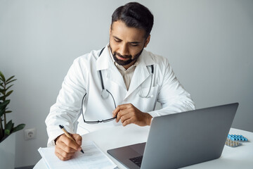 Doctor write patient diagnosis on online consultation sitting front of laptop