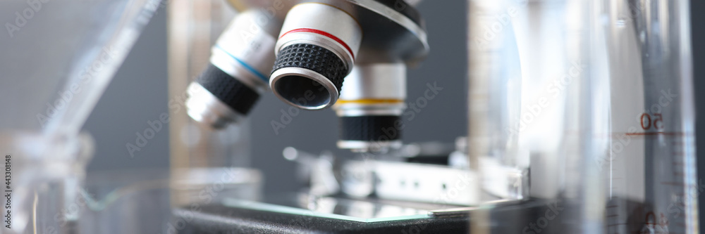 Research microscope in laboratory is next to test tubes. - obrazy, fototapety, plakaty 