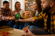 Group of friends on a house party drinking beer and eating pizza