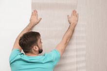 Man Hanging Stylish Wall Paper Sheet Indoors