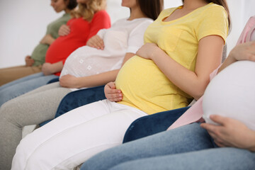 Wall Mural - Group of pregnant women at courses for expectant mothers on blurred background, closeup