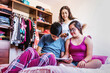 © Marcos - mexican female teenager with Down syndrome sitting on bed having fun with her family in home in disability concept in Latin America