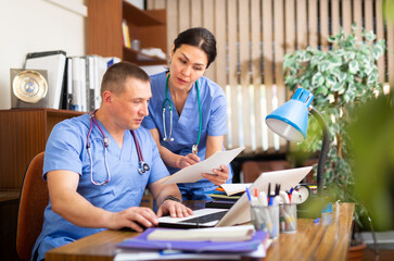 Two professional doctors checking the patient papers in a doctor office in clinic