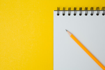 Wall Mural - Top view of Notebook, pencil on a yellow background  and copy space