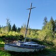 An old wooden boat with a tall mast has put out to pasture in a green field in Western Oregon. 