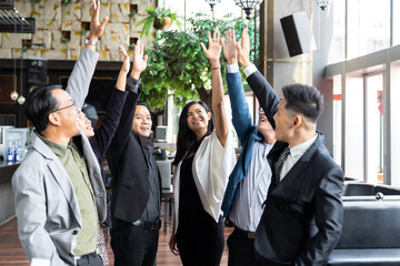 Wall Mural - Asian business team wearing suit raising hands in conference room. Diverse business people working and sharing ideas concept in the office. business, people