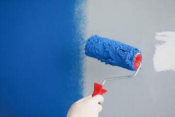 Wall Mural - Master painter painting wall with roller blue closeup