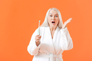 Canvas Print - Surprised mature woman with tooth brush on color background