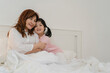 © tirachard - Asian grandmother relax at home. Senior Chinese, grandma happy relax with young granddaughter girl enjoy close her eyes surprise playing together lying on bed in bedroom at home at night concept.