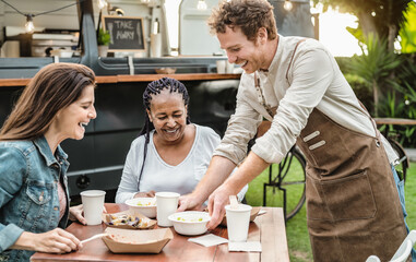 Young Food truck owner serving meal to customers table - Happy multiracial females having fun lunching together