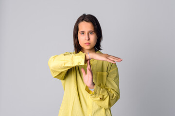 Portrait of beautiful teen girl making time out gesture, looking at camera, wearing casual yellow shirt