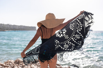 Wall Mural - Back view of a girl with a cape on the seashore.