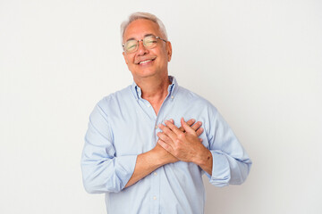 Senior american man isolated on white background has friendly expression, pressing palm to chest. Love concept.