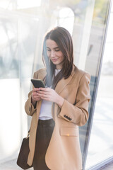 Smiling business woman using phone in office. Small business entrepreneur looking at her mobile phone and smiling.