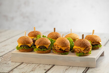 Set Of Beef And Chicken Mini Burgers With Cheese And Lettuce With Sticks On A Wooden Background