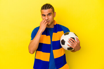 Young venezuelan man watching soccer isolated on yellow background biting fingernails, nervous and very anxious.