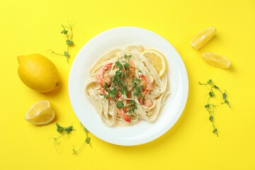 Plate of tasty shrimp pasta on yellow background