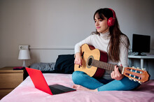 Woman Playing Guitar And Watching Online Lesson