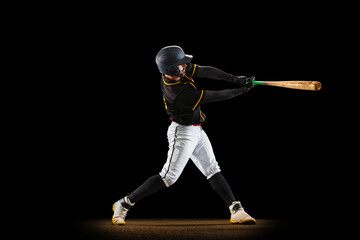 Professional baseball player, pitcher in sports uniform and equipment playing baseball isolated on black studio background in neon light. Team sport concept