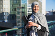 © ADDICTIVE STOCK - Stylish Muslim businesswoman with coffee and folder in city