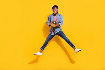 Wall Mural - Full length photo of crazy dark skin young man jump up hold hands disco ball isolated on yellow color background