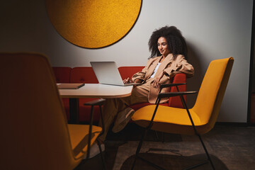 Smiling woman with laptop in the colorful lounge room