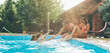 © BalanceFormCreative - Group of friends making fun and play in the swimming poolThey smiling and joying in hot summer day.
