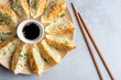 Gyoza or jiaozi, chinese fried dumplings served with soy sauce and sesame seeds on bamboo plate, top view