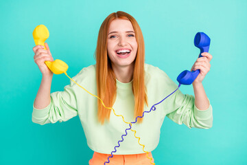 Photo of optimistic millennial lady hold phones wear sport clothes isolated on vivid teal color background