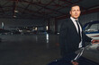 © Svitlana - Handsome man in suit standing by airplane in airport hangar