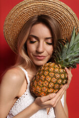 Wall Mural - Young woman with fresh pineapple on red background, closeup. Exotic fruit