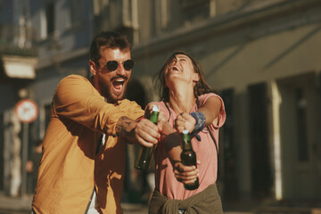 Wall Mural - Young couple dancing on the street and opening beer