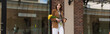 © LIGHTFIELD STUDIOS - stylish woman with paper cup holding tulips and walking outdoors, banner.
