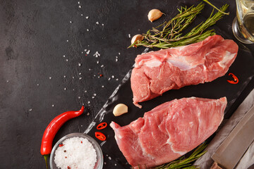 Wall Mural - raw pork shoulder  with chili pepper, rosemary, salt,  knife, napkin on a black background, red meat