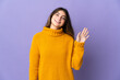 Young caucasian woman isolated on purple background saluting with hand with happy expression