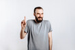 © Daria Lukoiko - Portrait of cheerful young handsome man smiling looking at camera pointing finger upwards on white background with space for advertising mock up