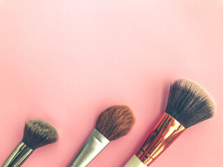 three tassels on a pink matte background. brushes for blush, powder, foundation and contouring. a tool for the work of a makeup artist. Beautiful face