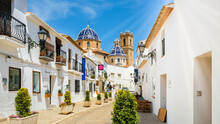 Street Of Altea Old Town In Spain. Beautiful Village With White Houses And Blue Domed Church Our Lady Of Solace. Popular Spanish Tourist Destination, Costa Blanca Region