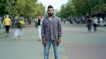 zoom-in time lapse portrait of attractive middle eastern man standing alone among people passing by 