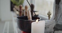 Close-up Of Lighting An Incense Stick From A Candle Standing Near Tibetan Singing Bowl On A Windowsill In Yoga Studio. Meditation And Relaxation Concept.