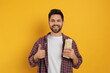 Happy young man with tasty shawarma showing thumb up on yellow background