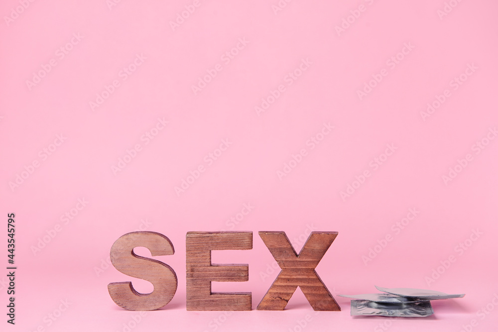 Word SEX with condoms on color background