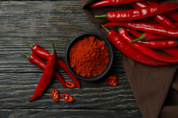 Red chili peppers and powder on rustic wooden background