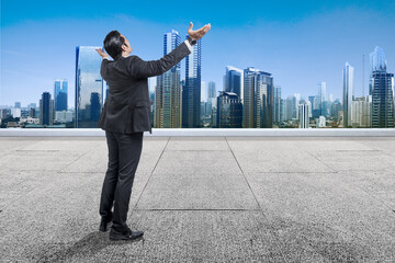 Wall Mural - Rear view of Asian businessman standing with raised hand on the rooftop